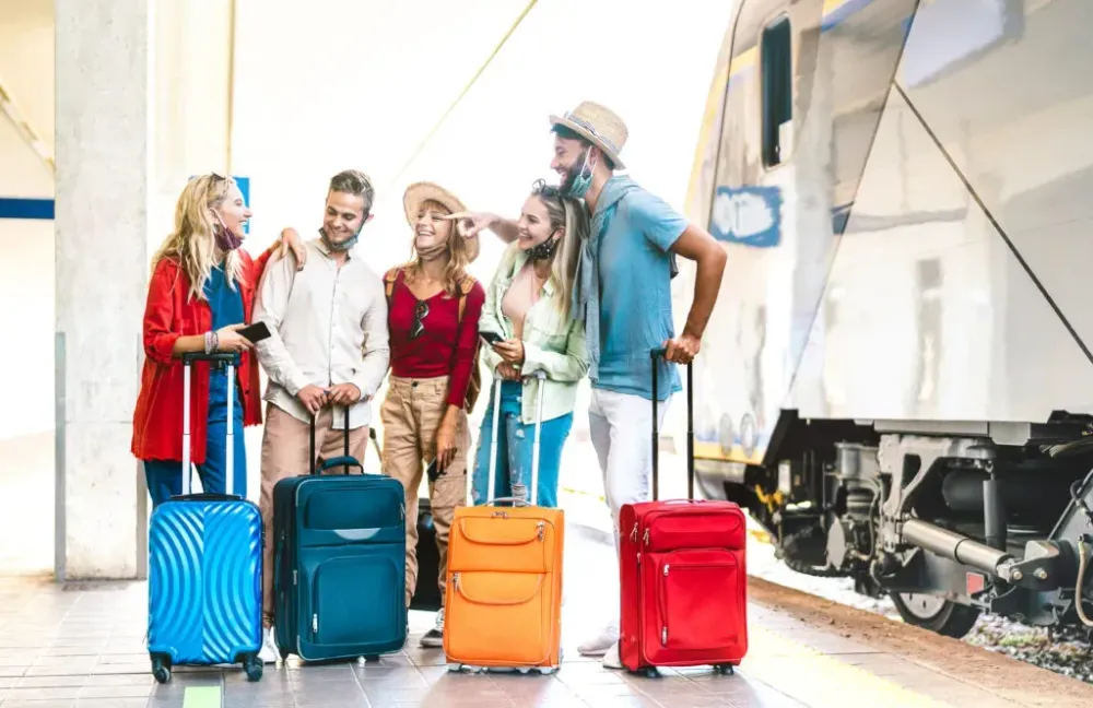 Group of friends chatting and waiting on a train platform with their luggage